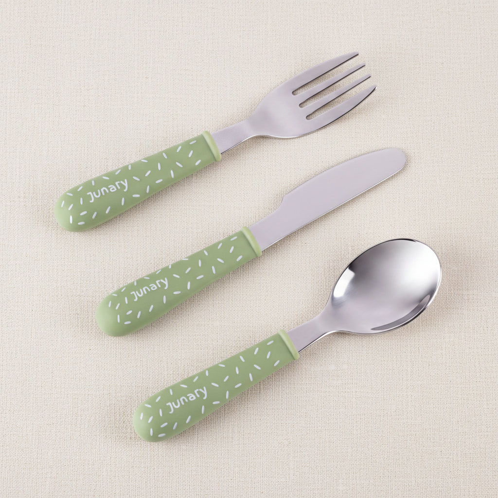 Three-piece baby cutlery set with green handles and silver stainless steel heads, featuring a fork, knife, and spoon on a white background.