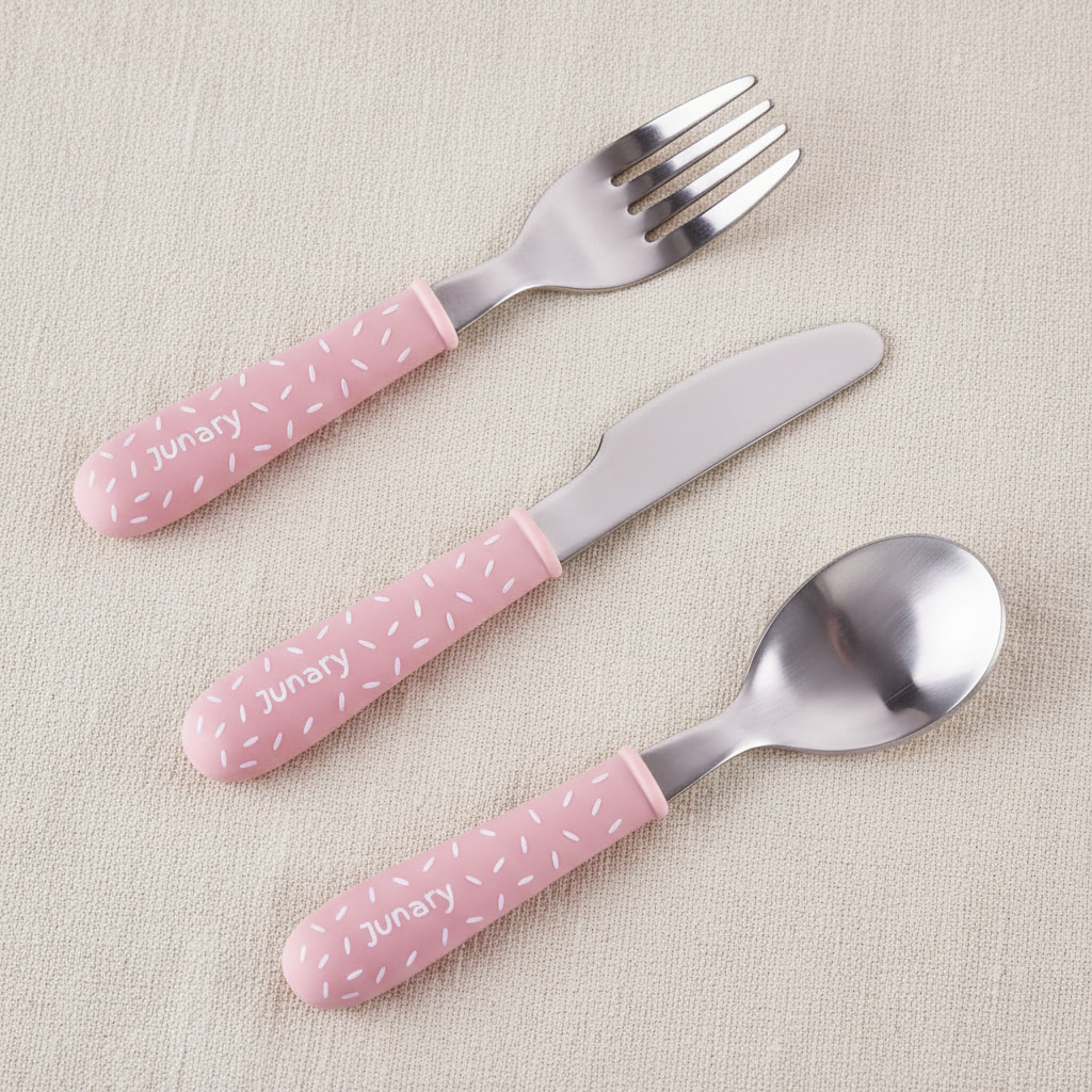 Three-piece baby cutlery set with pink speckled handles and stainless steel blades, including a fork, knife, and spoon, on a white background.