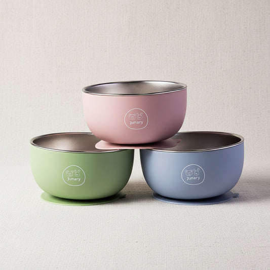 Three pastel-colored baby bowls stacked in a pyramid on a white background. The top bowl is dusty pink, the bottom left is sage green, and the bottom right is periwinkle blue.