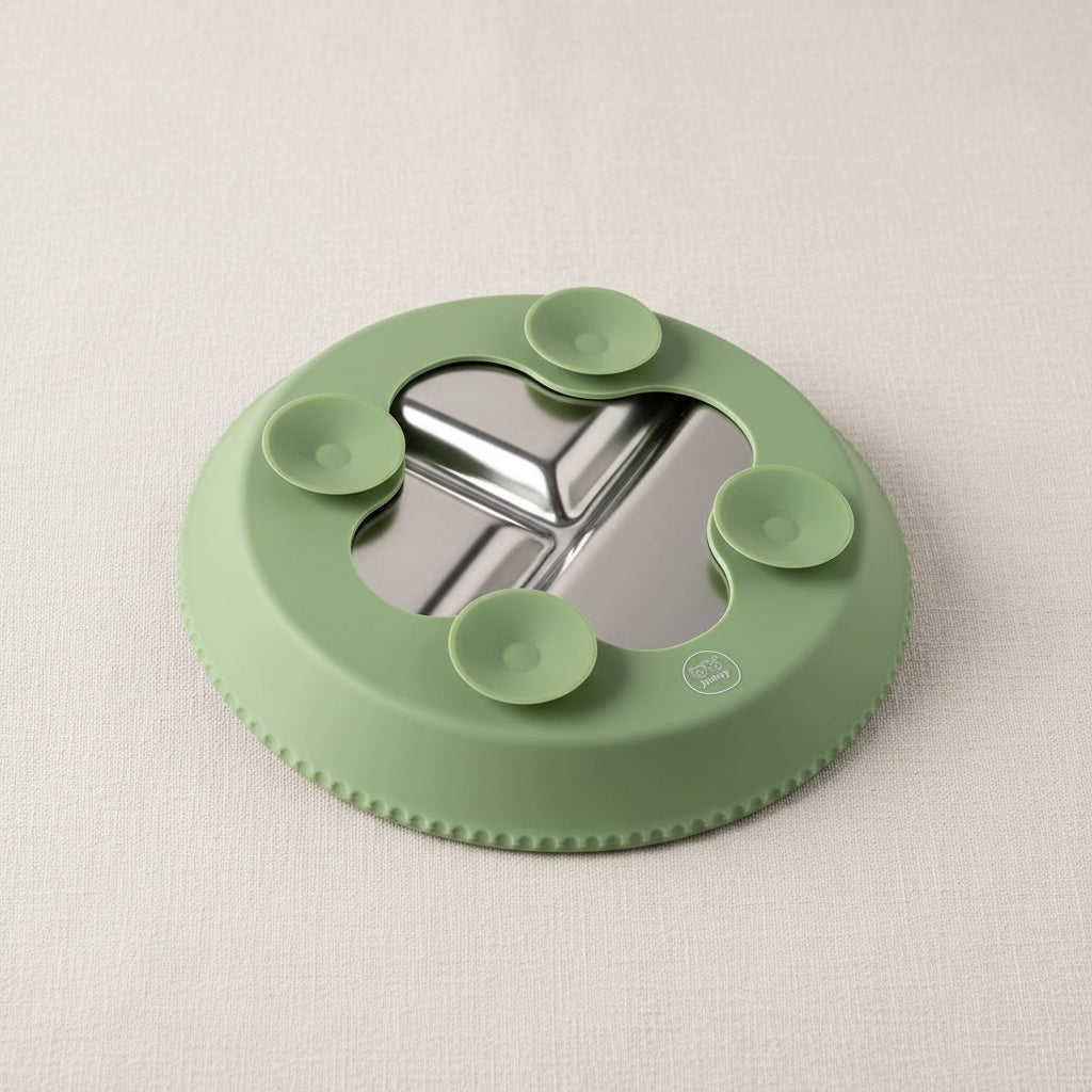 A green silicone suction base for a three-compartment stainless steel divided plate, shown from a bottom angle.