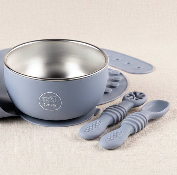 A baby feeding set including a light blue silicone bib, a stainless steel bowl, and three textured silicone spoons, all in a matching light blue color, arranged on a white background.