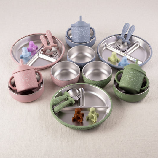 Sets of stainless steel and silicone feeding accessories arranged on a white background, including divided plates, bowls, cups, spoons, forks, blue, and  evergreen.